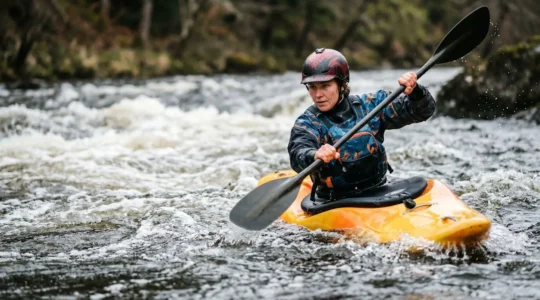 Kayaker maneuvering through whitewater rapids with safety equipment and proper technique