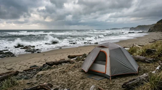 Coastal camping tent securely anchored against strong winds near dramatic ocean shoreline