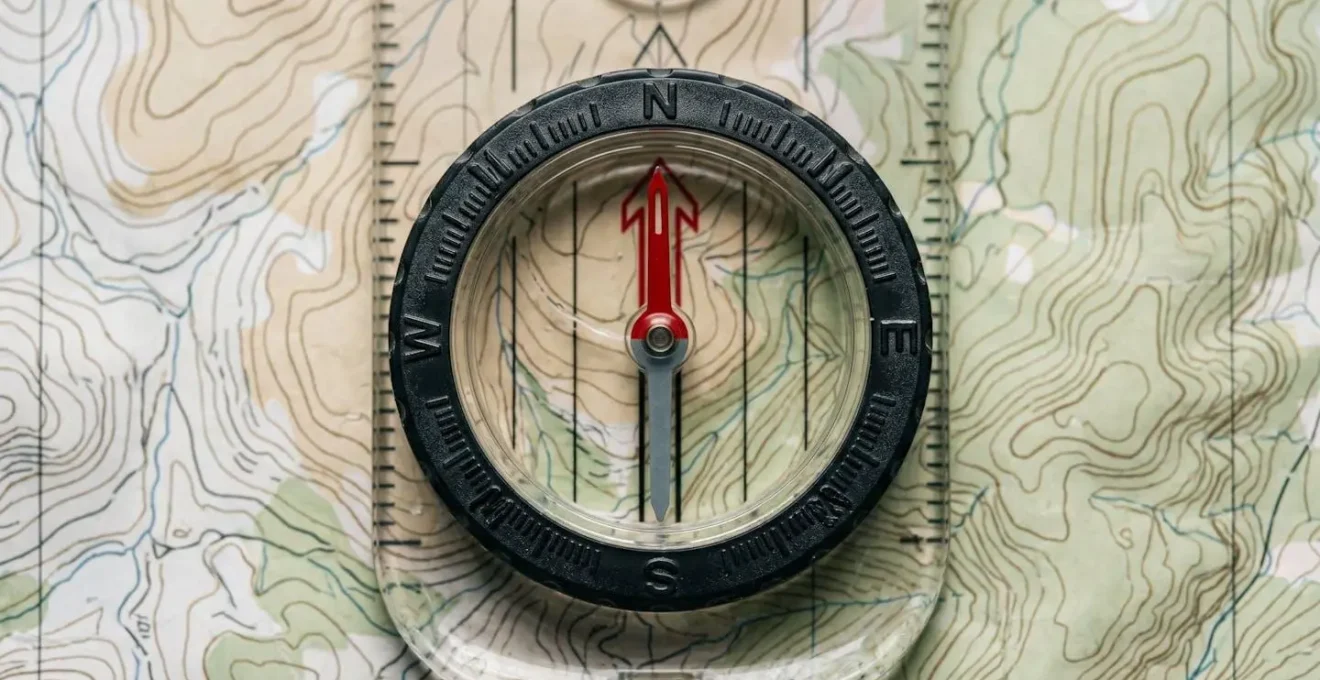 Extreme close-up of compass placed on topographic map showing precise navigation planning detail