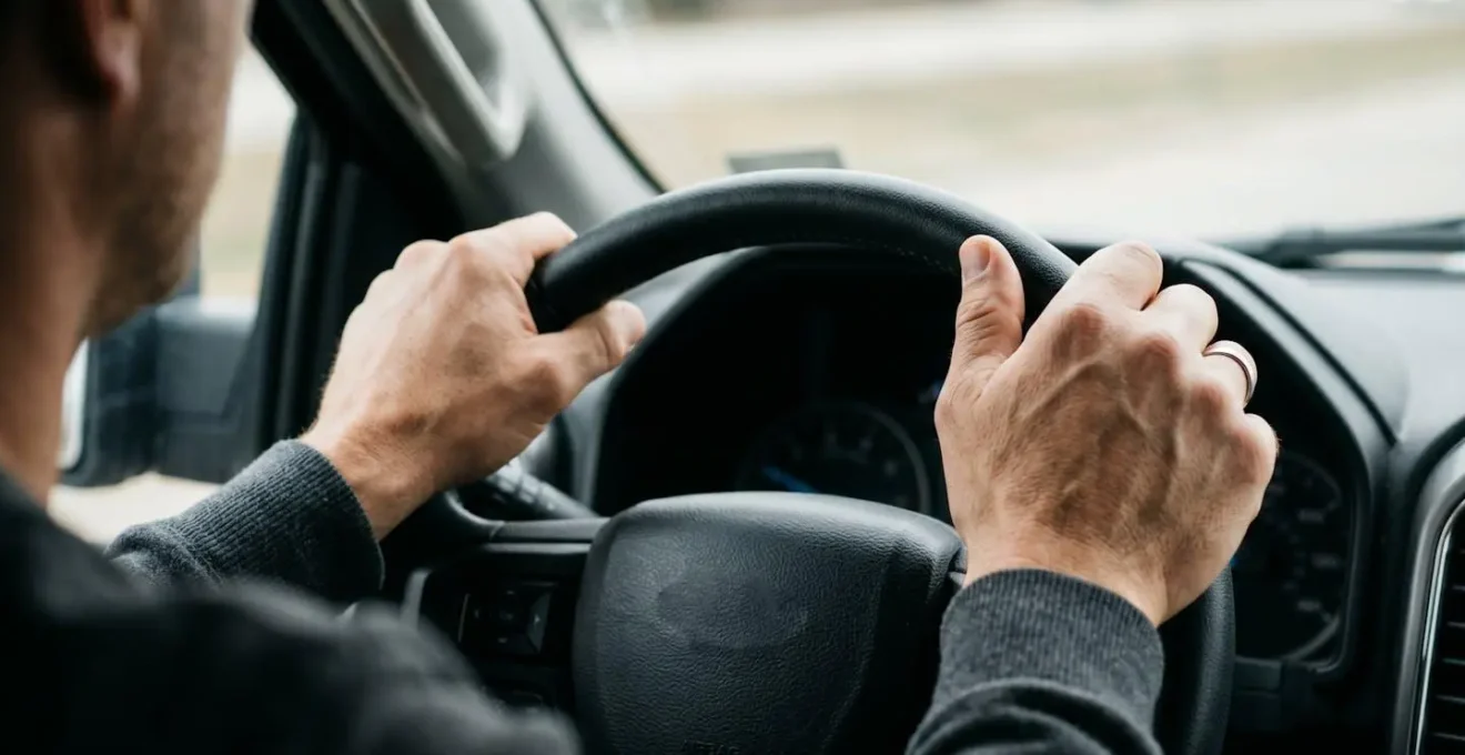 Close-up of a driver's hands gripping the steering wheel firmly during a towing emergency, showing tension and focused control