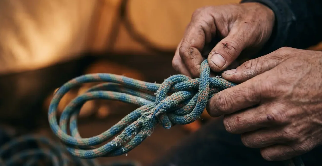Close-up of hands creating butterfly coil with climbing rope in tent interior