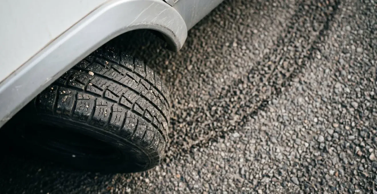Dramatic overhead macro view of RV rear corner wheel and ground surface showing tight turning radius perspective with textural detail of asphalt