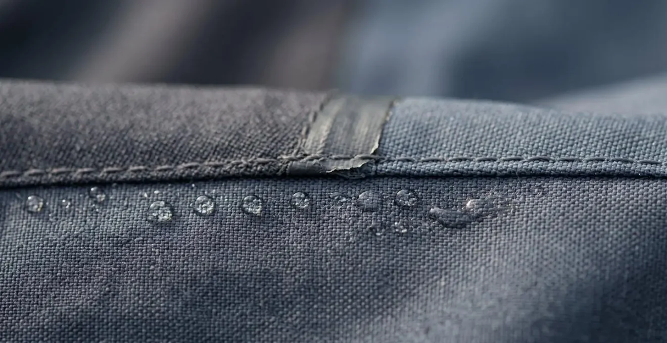 Extreme close-up of weathered jacket seam with water beading on fabric surface