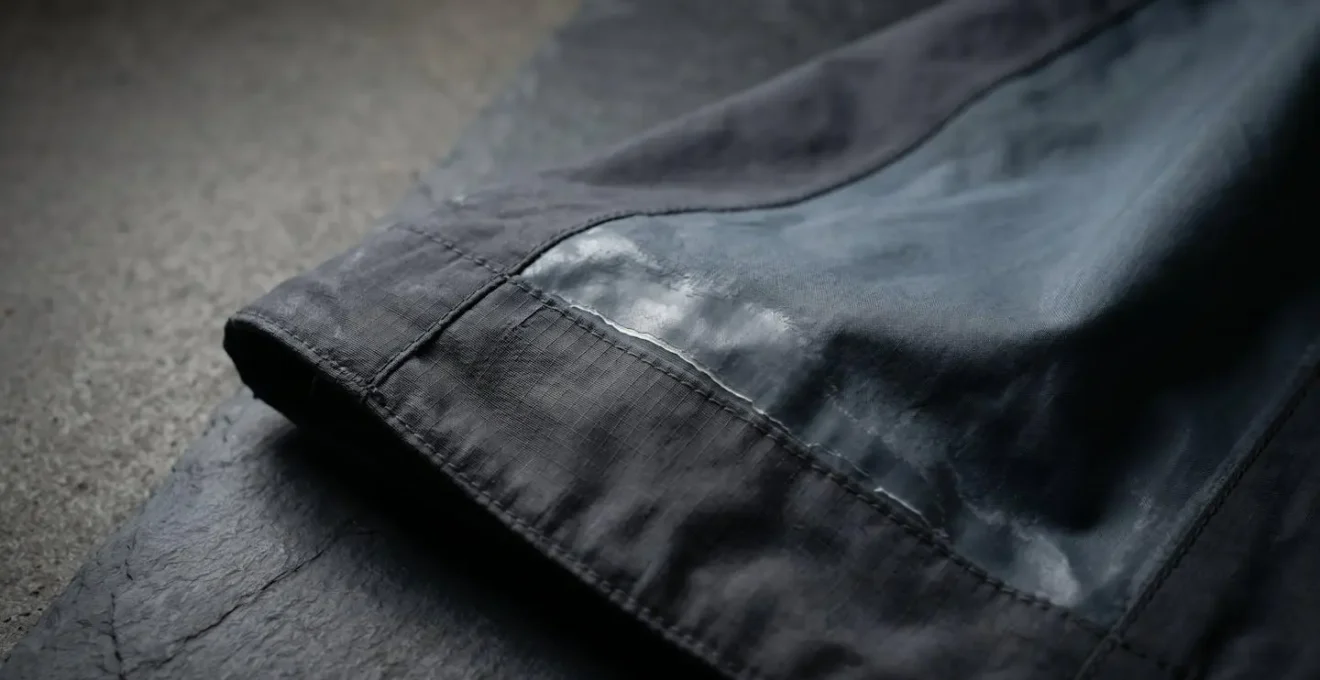 Close-up view of peeling waterproof coating on outdoor gear fabric showing degradation