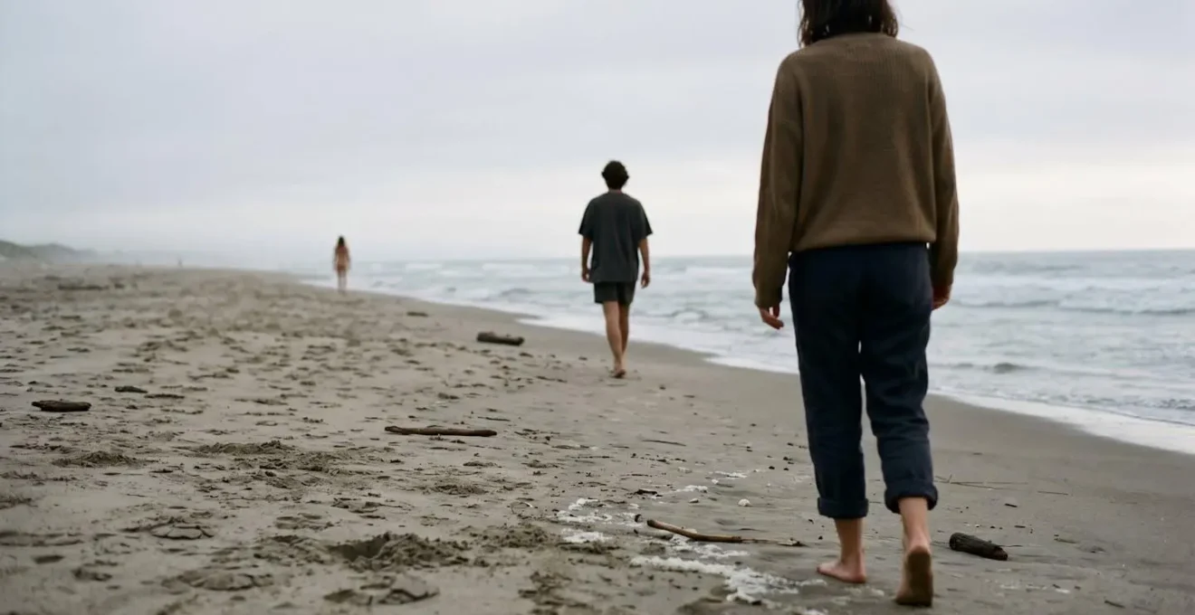 Silhouetted figures maintaining respectful distance on sandy beach gradient from clothed to unclothed areas